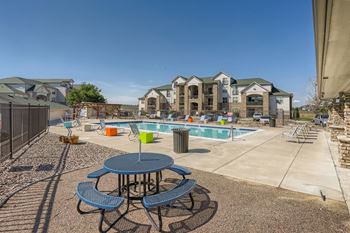 A large outdoor swimming pool with a table and chairs around it at Fox Run Lofts Apartments, Englewood CO.